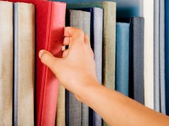 Image of a hand selecting a red book from a bookshelf